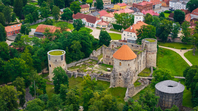 Aerial view of Cesis Castle with its historic stone towers, red roofs, and surrounding lush green parkland in Cesis, Cesis Municipality, Latvia.