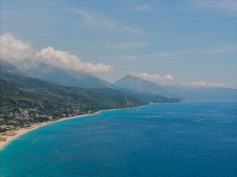 Aerial view of Qeparo Fushe coastline with turquoise waters, sandy beaches, and lush green mountains rising from the shore in Qeparo Fushe, Vlore County, Albania.