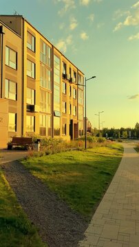 Modern Residential Building at Sunrise in Neighborhood. Residential condominium block building at Lush Greenery and Pathways. Walkway in contemporary apartment condo complex.