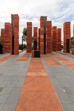 Tall sandstone pillars with ANZAC inscriptions stand across a paved plaza at Pukeahu National War Memorial Park in Wellington, New Zealand