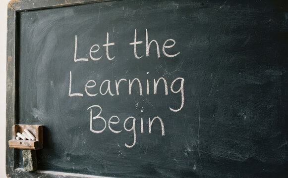 Let the learning begin message written on a vintage black chalkboard with chalk representing education and school concept