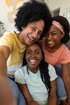 African American family smiling and leaning toward camera on couch in living room with framed art