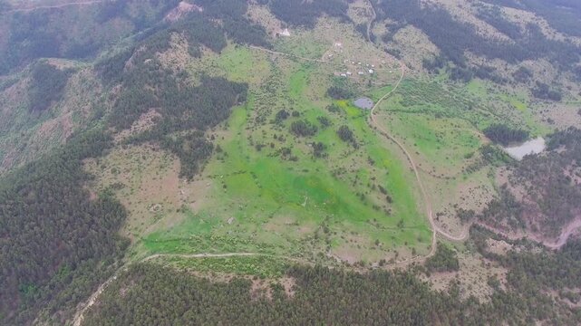 Aerial view of deforestation scars across dense forest and meadow clearing landscape.