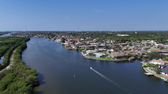 Single boat headed down Sykes Creek with waterfront homes on canals on one side and the Ulumay Wildlife Sanctuary on the other in Merritt Island, Florida.