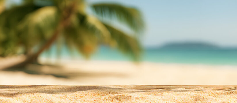 Blurry palm tree and tropical beach background with sandy surface, emphasizing a summer vacation and travel theme. There is ample copy space for adding text or images.