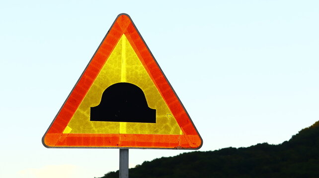 Reflective Triangular Road Sign Warning of Speed Bump or Road Hump Ahead Against Clear Sky