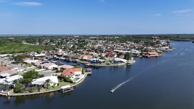 Single boat headed down Sykes Creek to the Indian River Lagoon with waterfront homes on canals in Merritt Island, Florida.