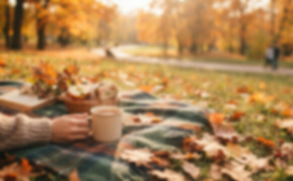 Cozy autumn picnic in the park with hot tea and warm blanket on yellow fallen leaves for autumn relaxation and cozy mood