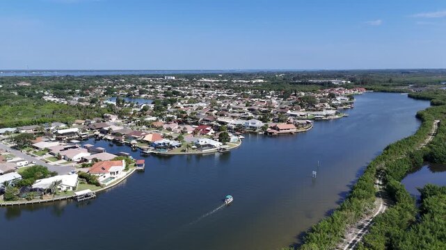 Single boat headed up Sykes Creek with waterfront homes on canals on one side and the Ulumay Wildlife Sanctuary on the other in Merritt Island, Florida.
