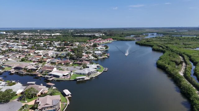 Single boat headed down Sykes Creek with waterfront homes on canals on one side and the Ulumay Wildlife Sanctuary on the other in Merritt Island, Florida.
