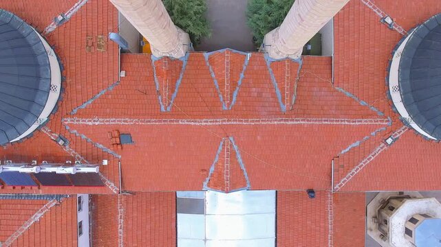 Aerial view shows mosque Quran school building with double minarets, twin domes, red tiles.