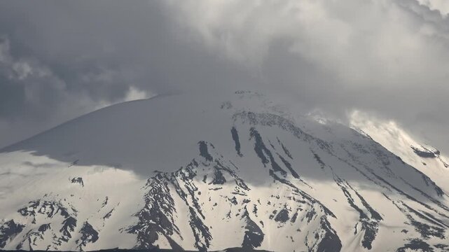 Mount Kilimanjaro Tanzania snowy summit rises through swirling clouds and alpine sky.