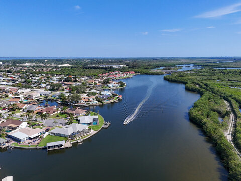 Single boat on Sykes Creek with waterfront homes on canals on one side and the Ulumay Wildlife Sanctuary on the other in Merritt Island, Florida.