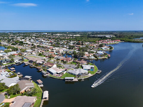 Boat passing by waterfront homes on canals with cul de sacs along Sykes Creek leading to the Indian River Lagoon in Merritt Island, Florida.
