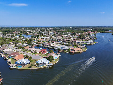 Boat passing by waterfront homes on canals with cul de sacs along Sykes Creek leading to the Indian River Lagoon in Merritt Island, Florida.