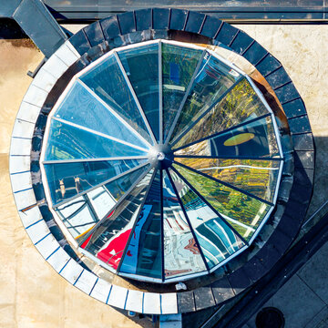 Aerial view of abstract reflections in a circular glass skylight with geometric metal framing in Belgrade, Serbia.