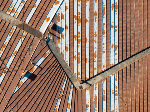 Aerial view of weathered metal rooftop patterns with rusted corrugated sheets and white painted stripes in Belgrade, Serbia.