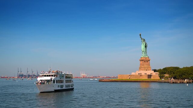 New York, USA, 4 Jule 2026 : Tour boat approaching Statue of Liberty in New York Harbor. Passengers fill the decks as the white vessel crosses harbor water beneath a clear blue sky.