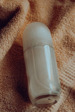 Roll on deodorant bottle containing a creamy formula, symbolizing daily hygiene, personal care, and freshness on a soft beige towel, representing comfort and luxury in beauty routines