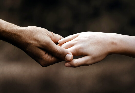 Closeup of an adult and child hand holding each other showing care and support