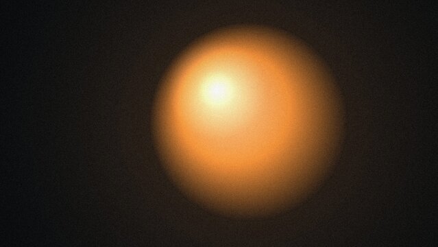Abstract glowing orangeyellow light orb radiating warm energy against a dark textured grainy background creating a mystical ambiance
