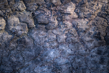 Fototapeta premium Lava texture with black basalt surface. Lava macro detail with rough cracks. Lava solidified magma pattern. Lava abstract dark background.