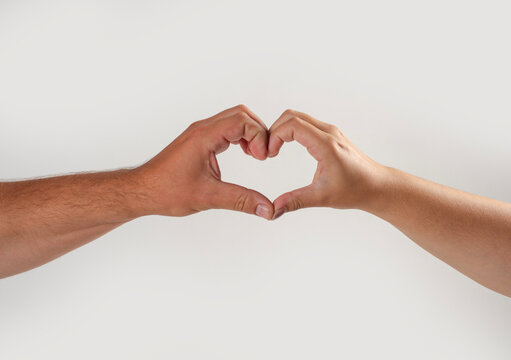 Heart gesture symbolizes love and trust. Heart gesture expresses couple affection. Human hands create heart gesture closeup. Two fingers complete heart gesture.