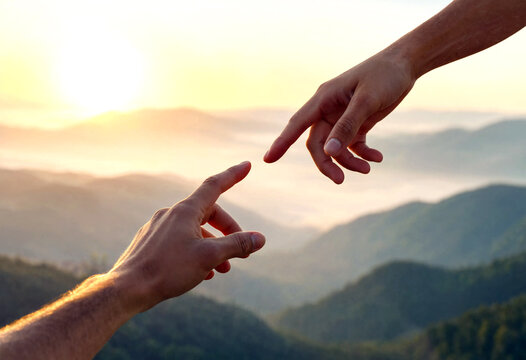Two hands almost touching with beautiful mountain landscape and sunset in the background symbolizing connection