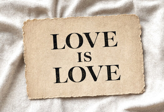 Vintage paper card with love is love message on soft fabric background perfect for romance themes