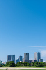 Fototapeta premium Blue sky and cityscape with high-rise apartments and green landscape, copy space background