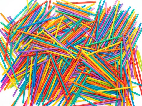 A vibrant pile of colorful drinking straws scattered randomly on a white background
