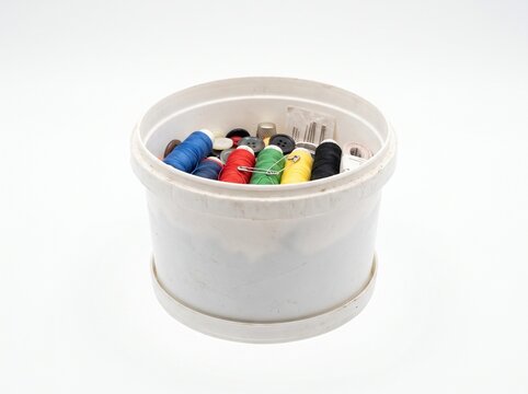 Sewing Kit Container Filled With Colorful Thread Spools Buttons Needles and Thimble Isolated on White Background