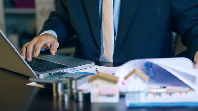 Businessman typing on laptop to prepare property quotation reports and housing price proposals.