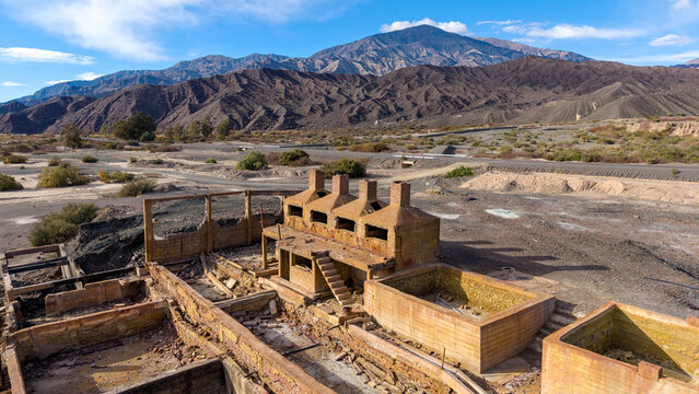 Aerial view of the historic Ruinas de Planta de Sulfato de Aluminio, featuring weathered brick structures and industrial basins in an arid landscape in Calingasta, San Juan, Argentina.