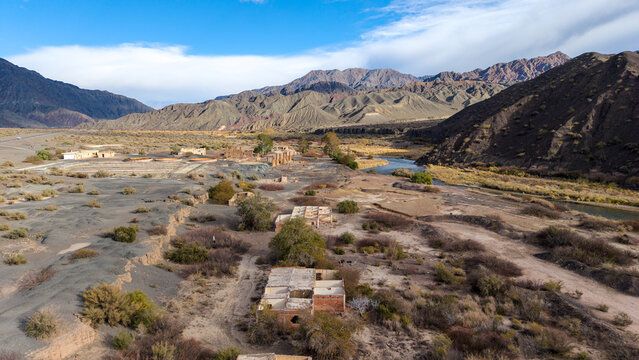 Aerial view of the Ruinas de Planta de Sulfato de Aluminio set in an arid desert landscape with a winding river and rugged mountains in Calingasta, San Juan, Argentina.