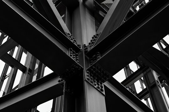 Stark, intersecting metal beams form a geometric, abstract pattern in black and white