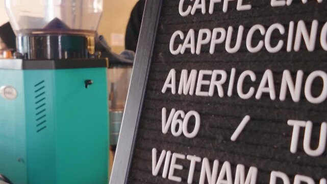 Coffee shop menu board displaying various beverage options next to a coffee grinder.