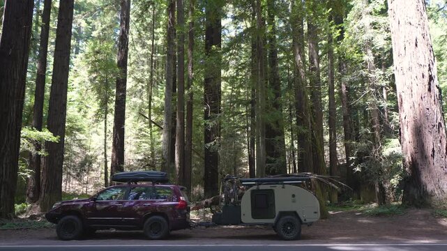 A woman enjoys lunch in her teardrop camper trailer parked by redwood trees in Navarro River Redwood State Park, Mendocino County.