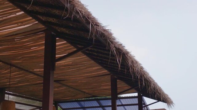 Traditional straw thatched roof structure against a clear sky background.
