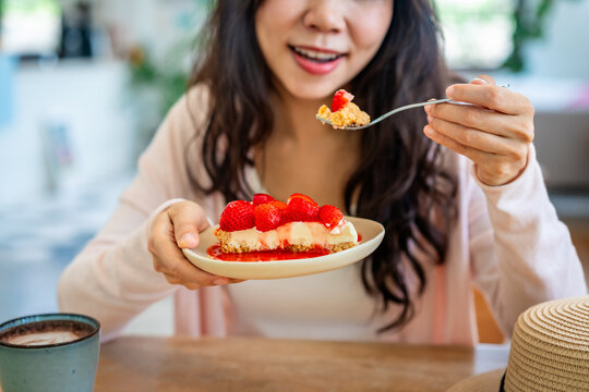 Sweet tooth and dessert indulgence concept: Happy woman enjoying strawberry cake and hot beverage on a sunny vacation day.
