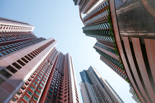 Dizzying perspectives of modern architecture emerge as high rise apartment blocks stretch upward from the bustling streets of Hong Kong under daylight