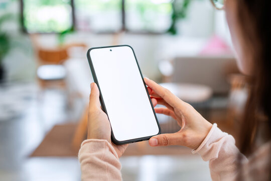 Close-up of female hands holding a mobile phone with empty white display, mockup space for design or app template.