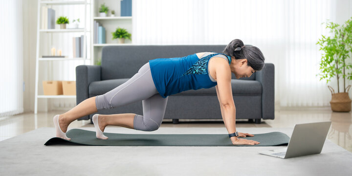 woman at home following an online workout tutorials on  laptop. fitness and wellness in home.