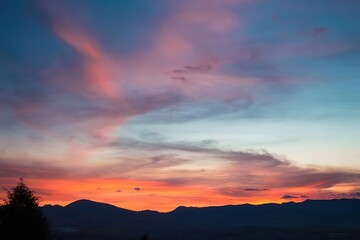 Fototapeta premium Panoramic Sunset Sky Deep Blue Vibrant Pink Fiery Orange Distant Mountains Twilight Landscape