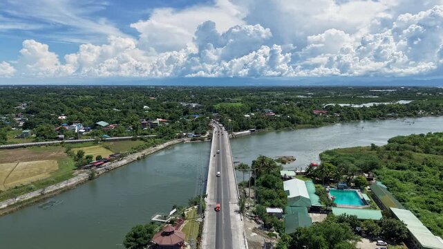 Forward flight aerial hyperlapse following highway traffic straight across the Cayanga Bridge in San Fabian, Pangasinan, Philippines