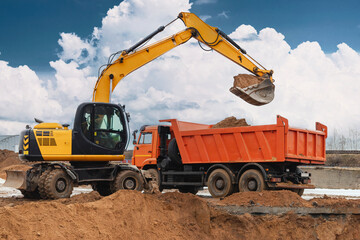 Excavator Loading Soil into Dump Truck at Active Construction Site © William