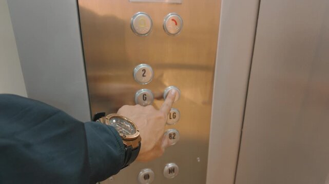 Close up of a man pushing a button inside a modern elevator.