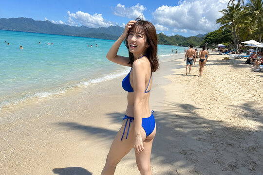青い水着で海辺を歩く女性