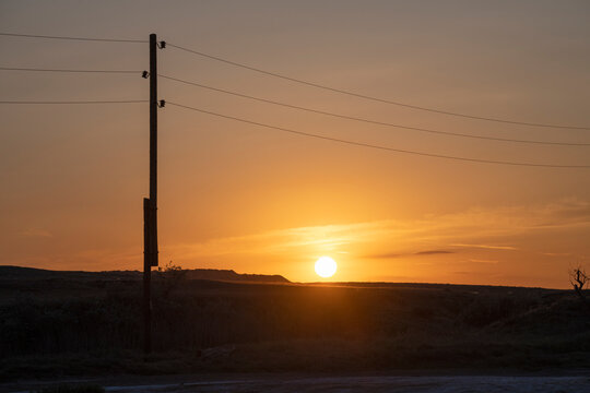 Pole with power line against the background of May sunset. Astrakhan region, Russia