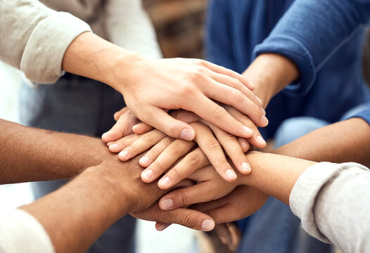 Diverse group of people stacking hands together showing unity teamwork and collaboration in a supportive gesture